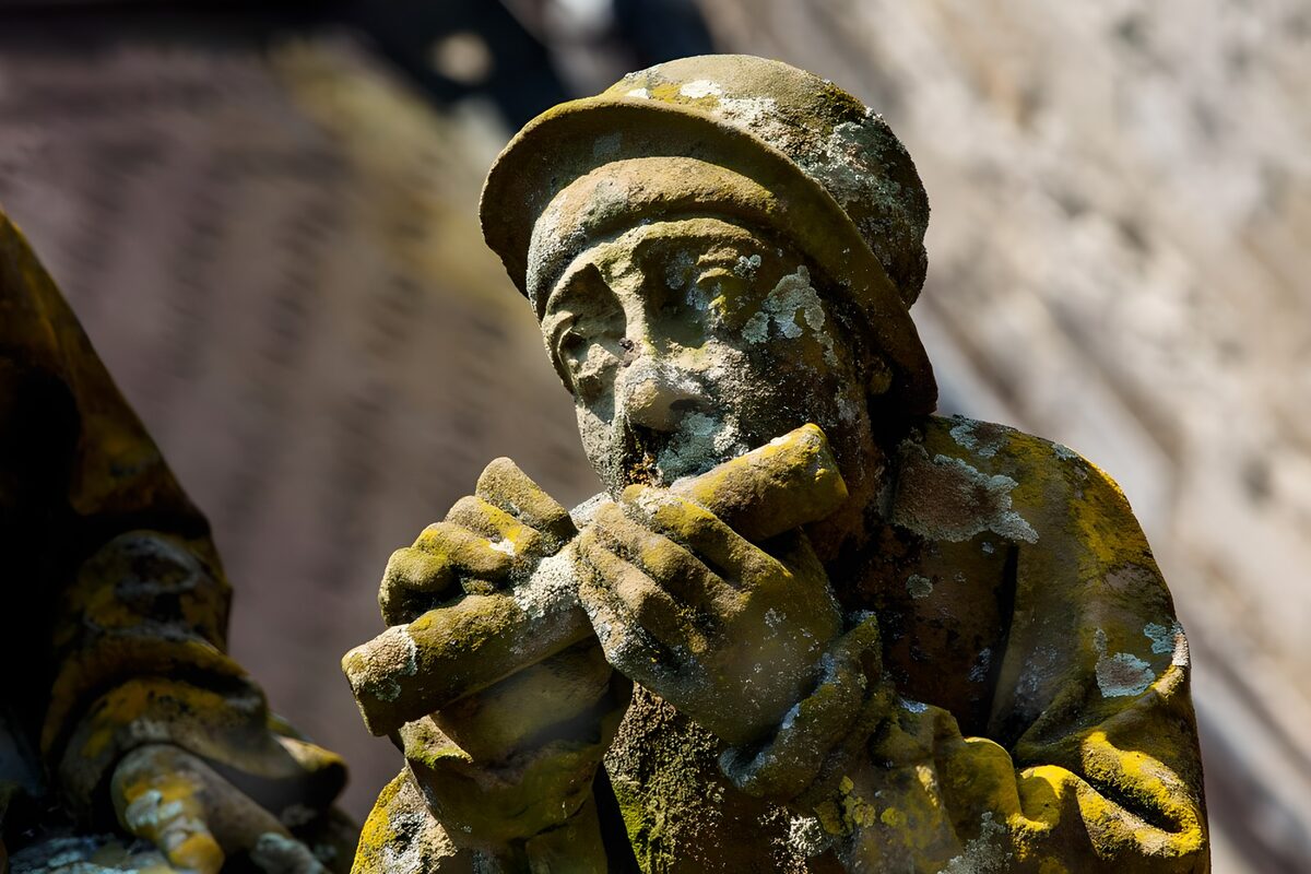 Weathered stone flute player in sunlight