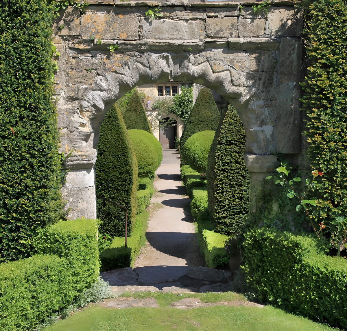 Stone arch and sunlit topiary
