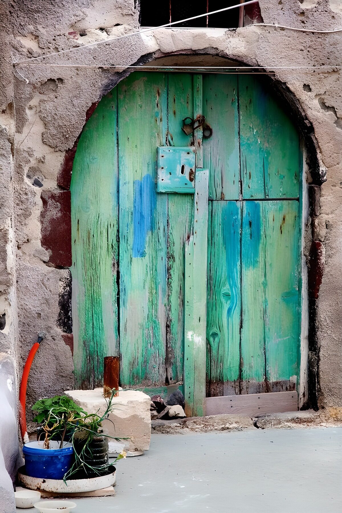 Weathered turquoise door in a stone arch