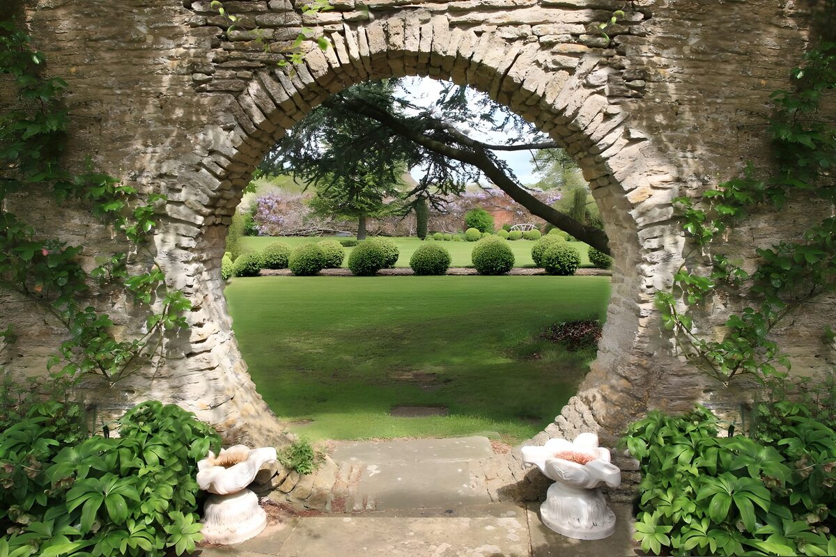 Spring garden through a round stone arch
