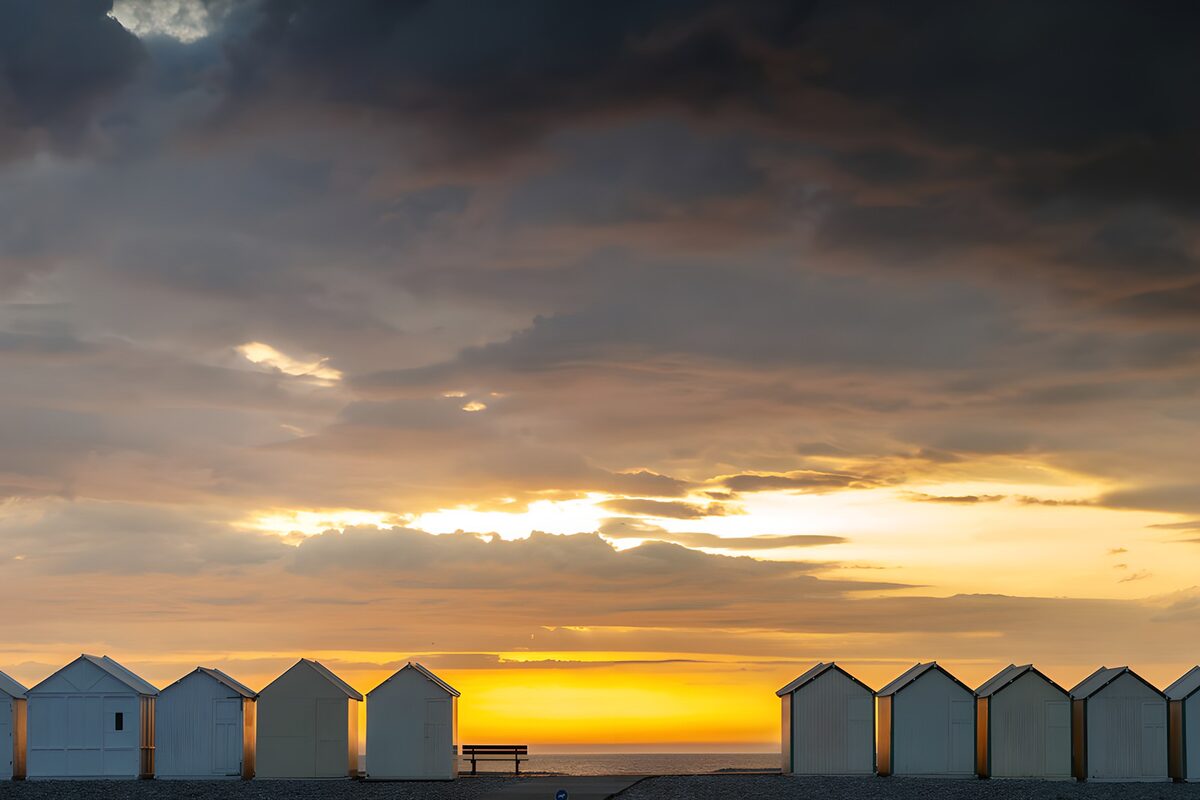 Beach huts beneath a glowing sunset