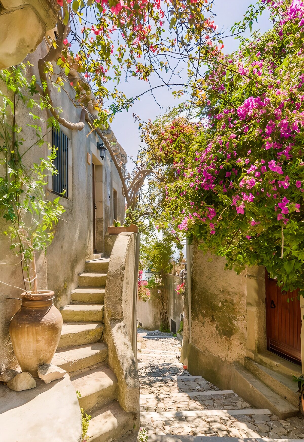 Sunlit stone alley with pink bougainvillea