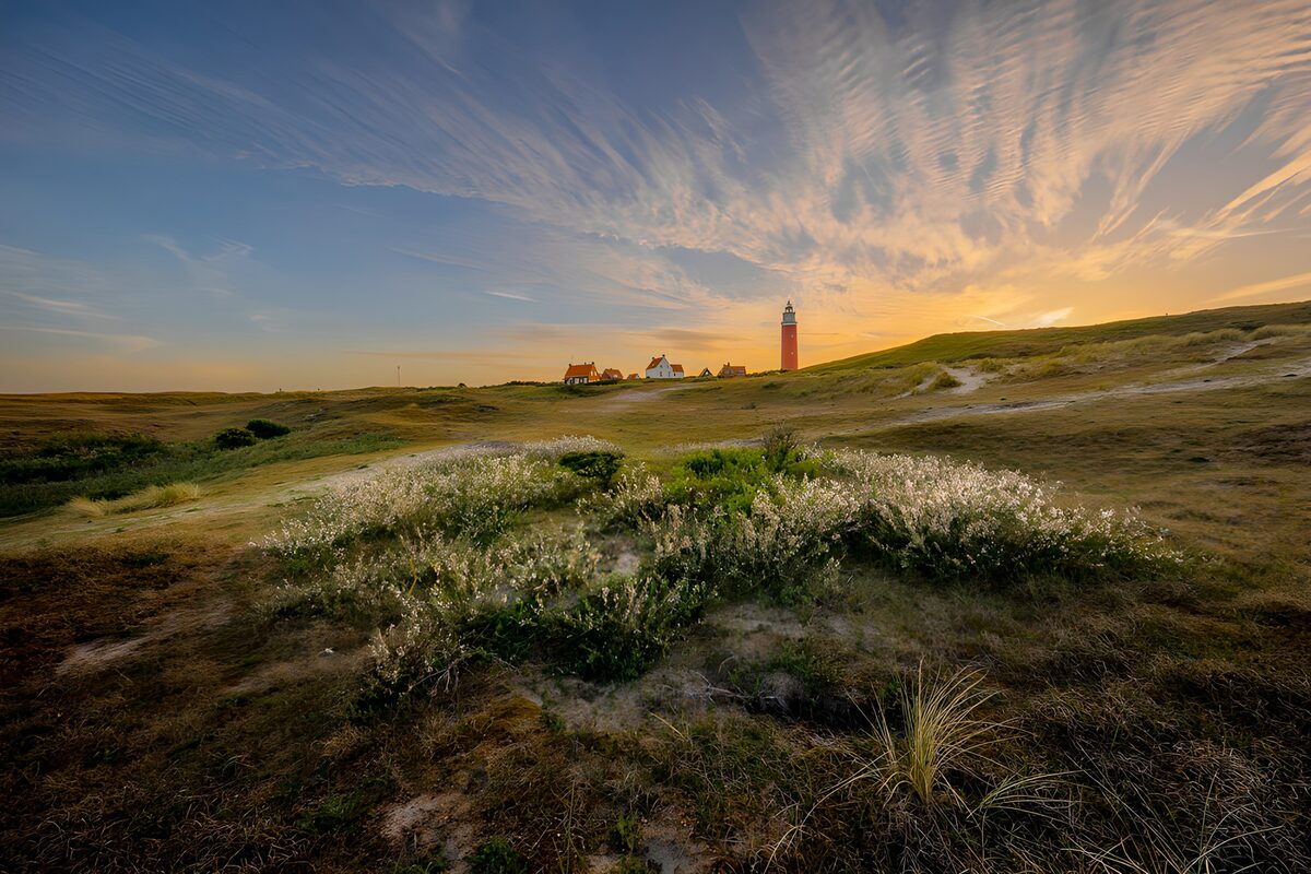 Red lighthouse and dunes in evening light