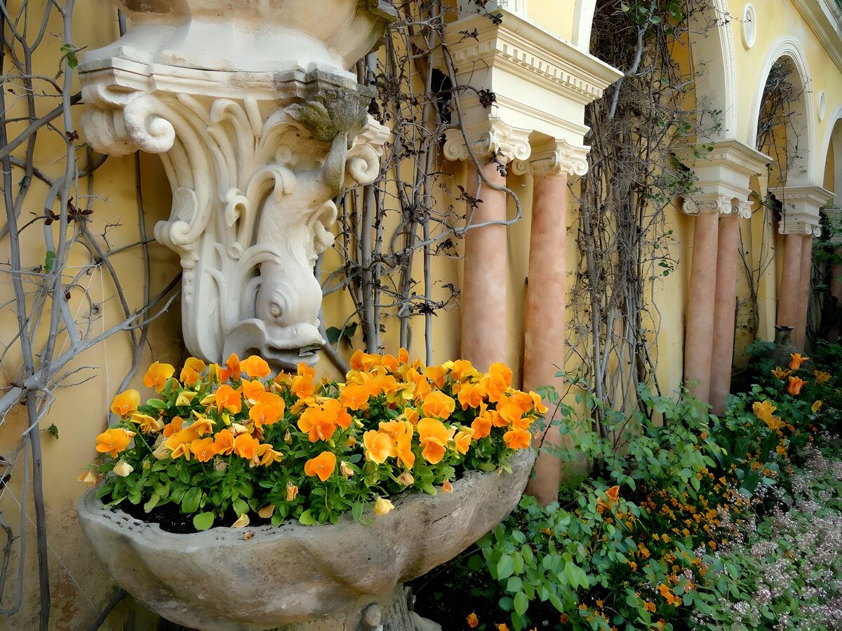 Pansies brighten an ornate garden facade