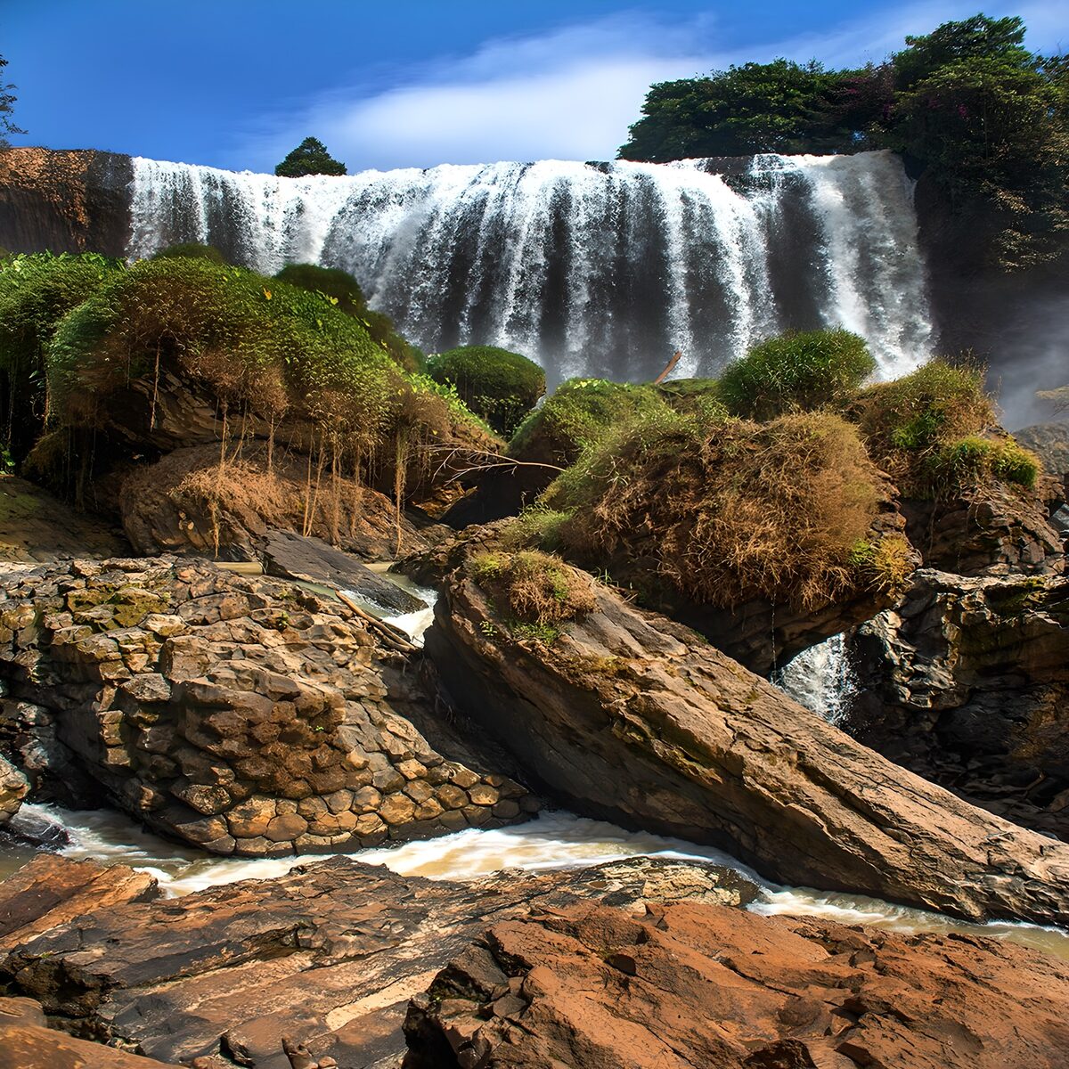 Sunlit waterfall over rugged rocks
