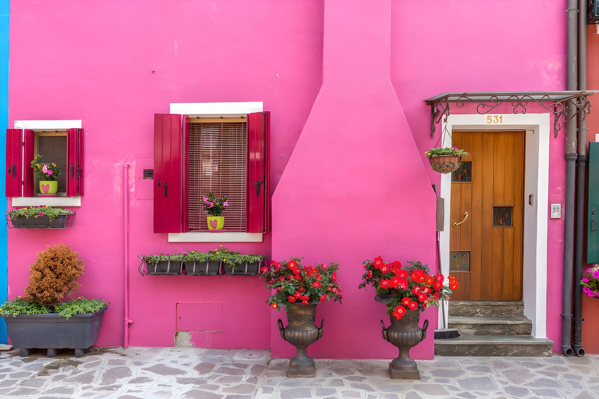 Bright pink facade with shutters and flowers