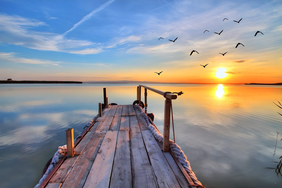 Weathered jetty on a quiet lake at sunset