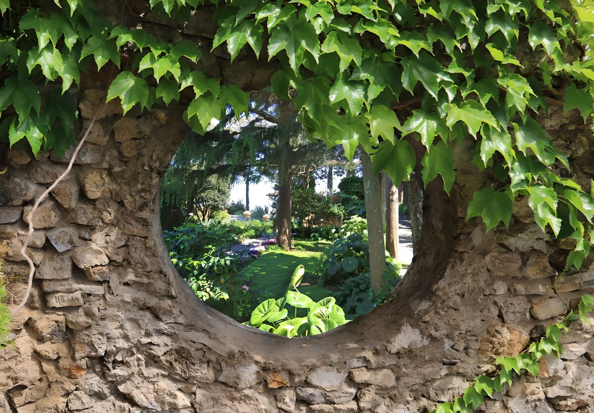 Round stone window onto a sunlit garden