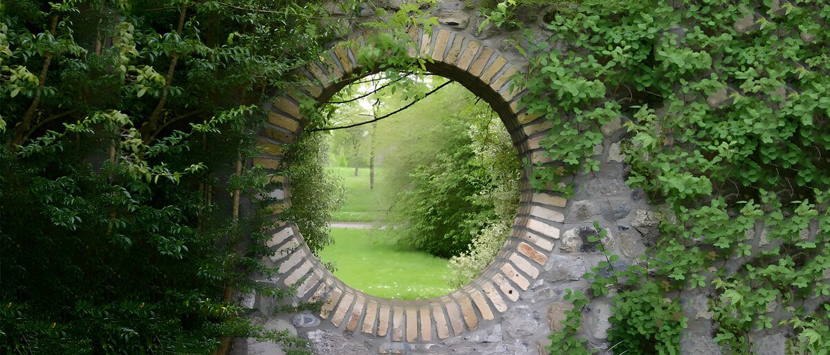 Round stone window onto a green garden