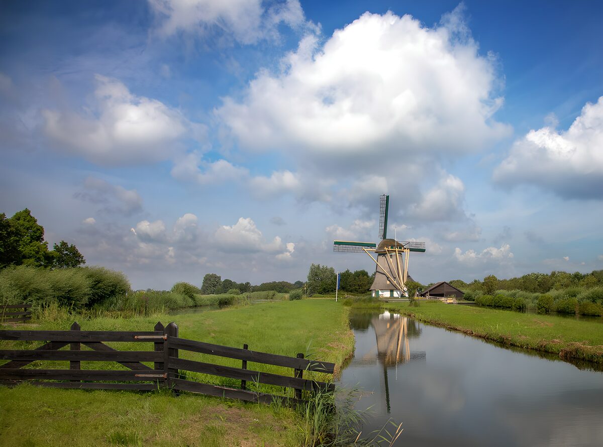 Windmill and canal under broad skies
