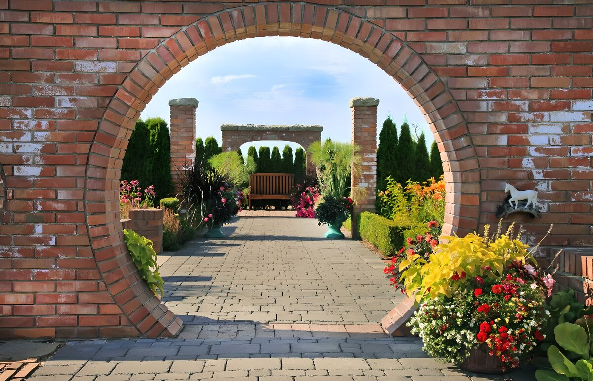 Sunny garden through a round brick arch
