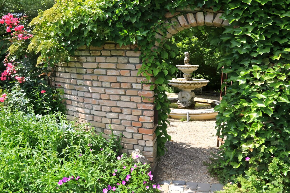 Sunlit fountain through a brick arch