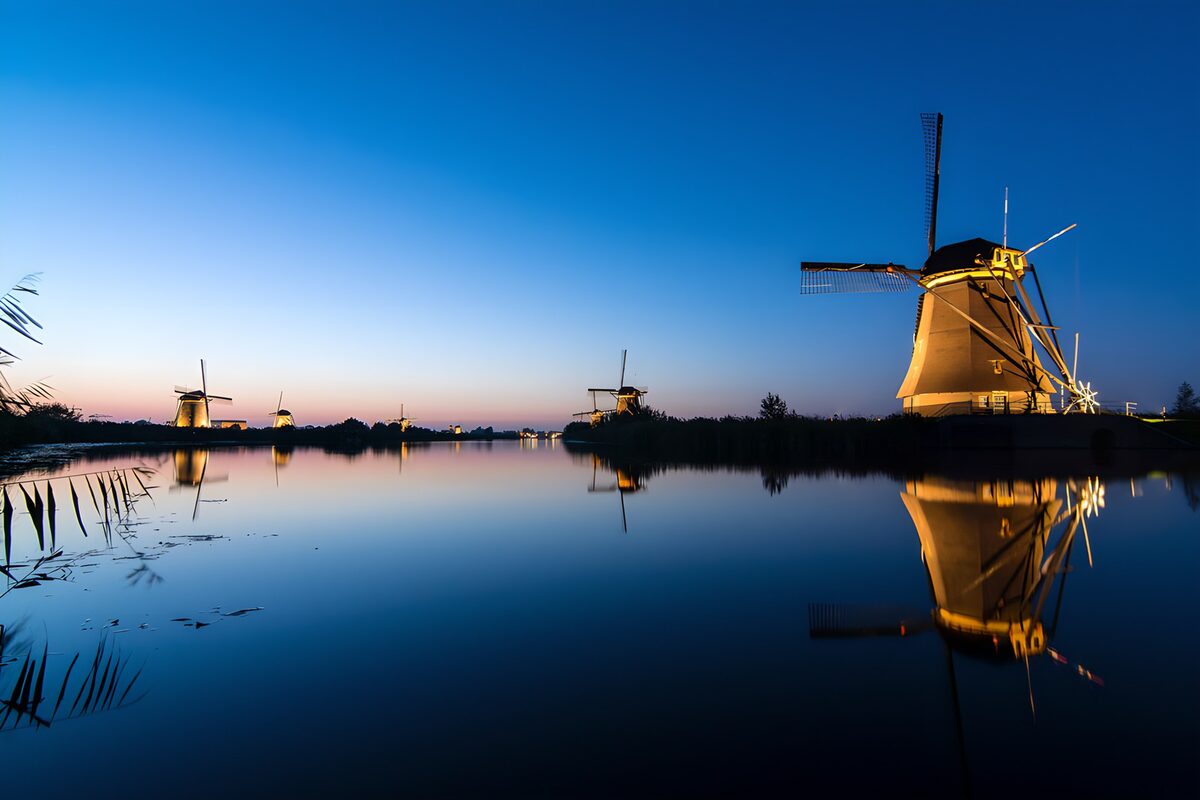 Windmills reflected in still water at dusk
