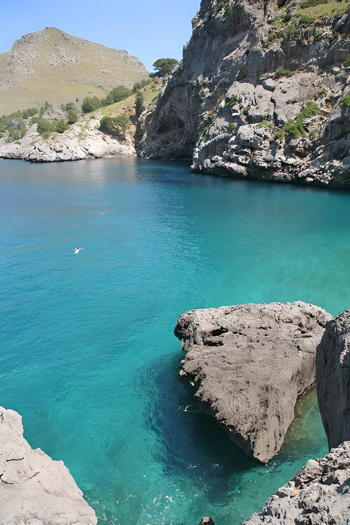 Sunlit rocks around a turquoise cove