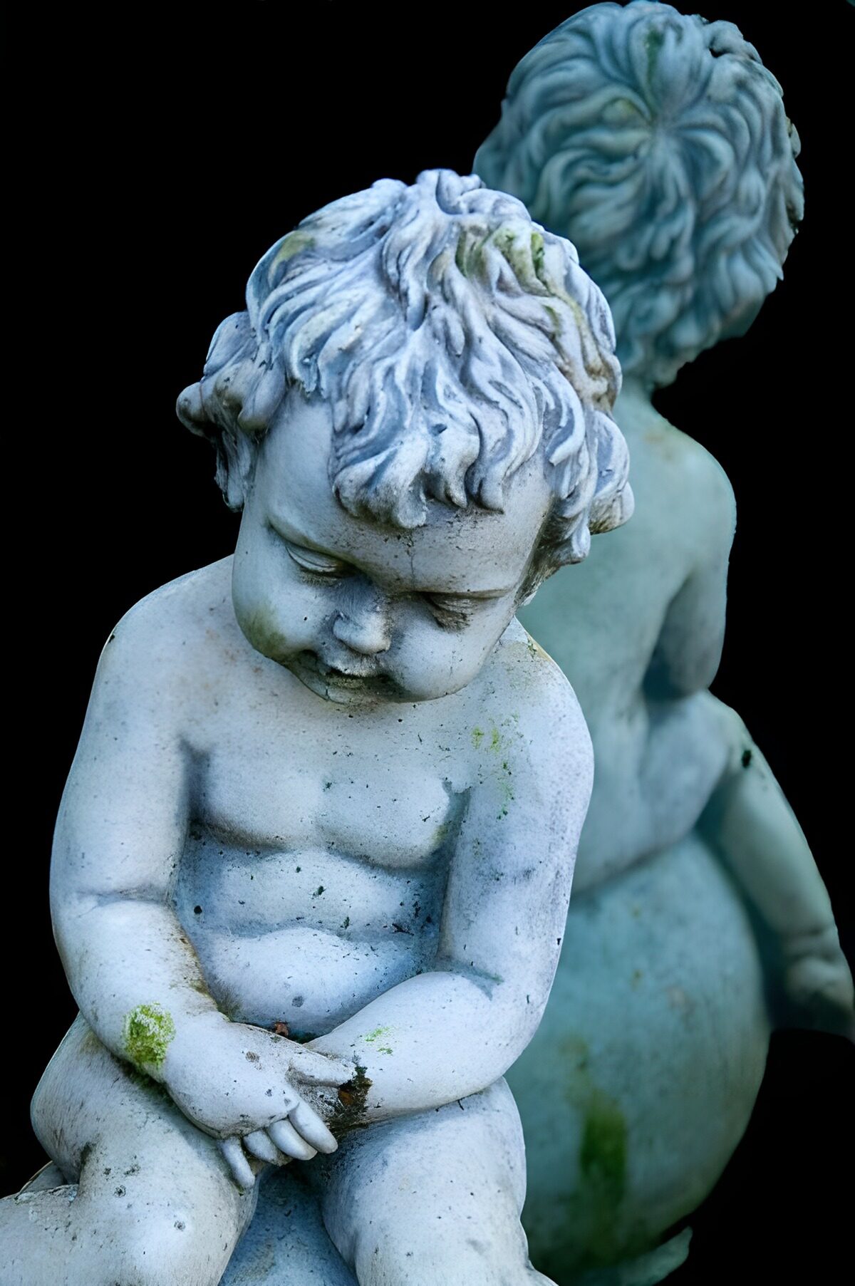 Two weathered stone children