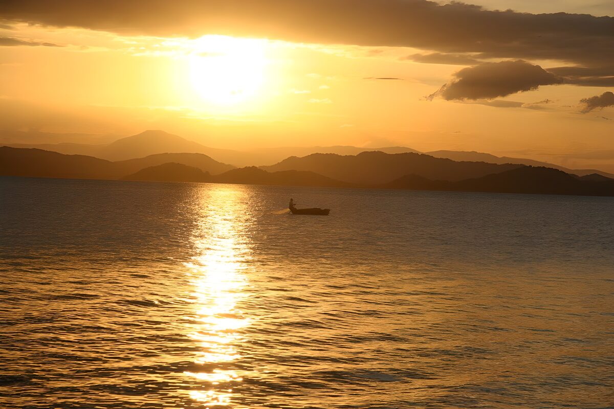 Lone boat on golden water at sunset
