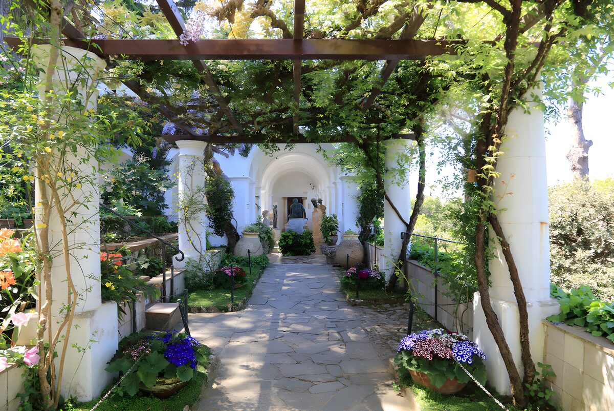 A shaded stone path beneath the pergola