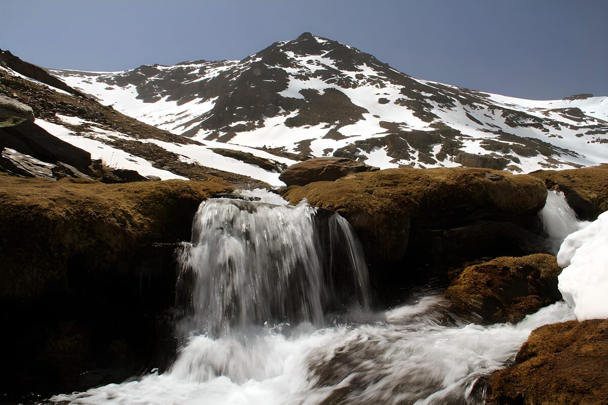 Rushing falls beneath a snowy mountain
