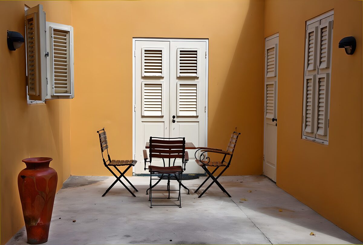 Sunlit yellow courtyard with white shutters