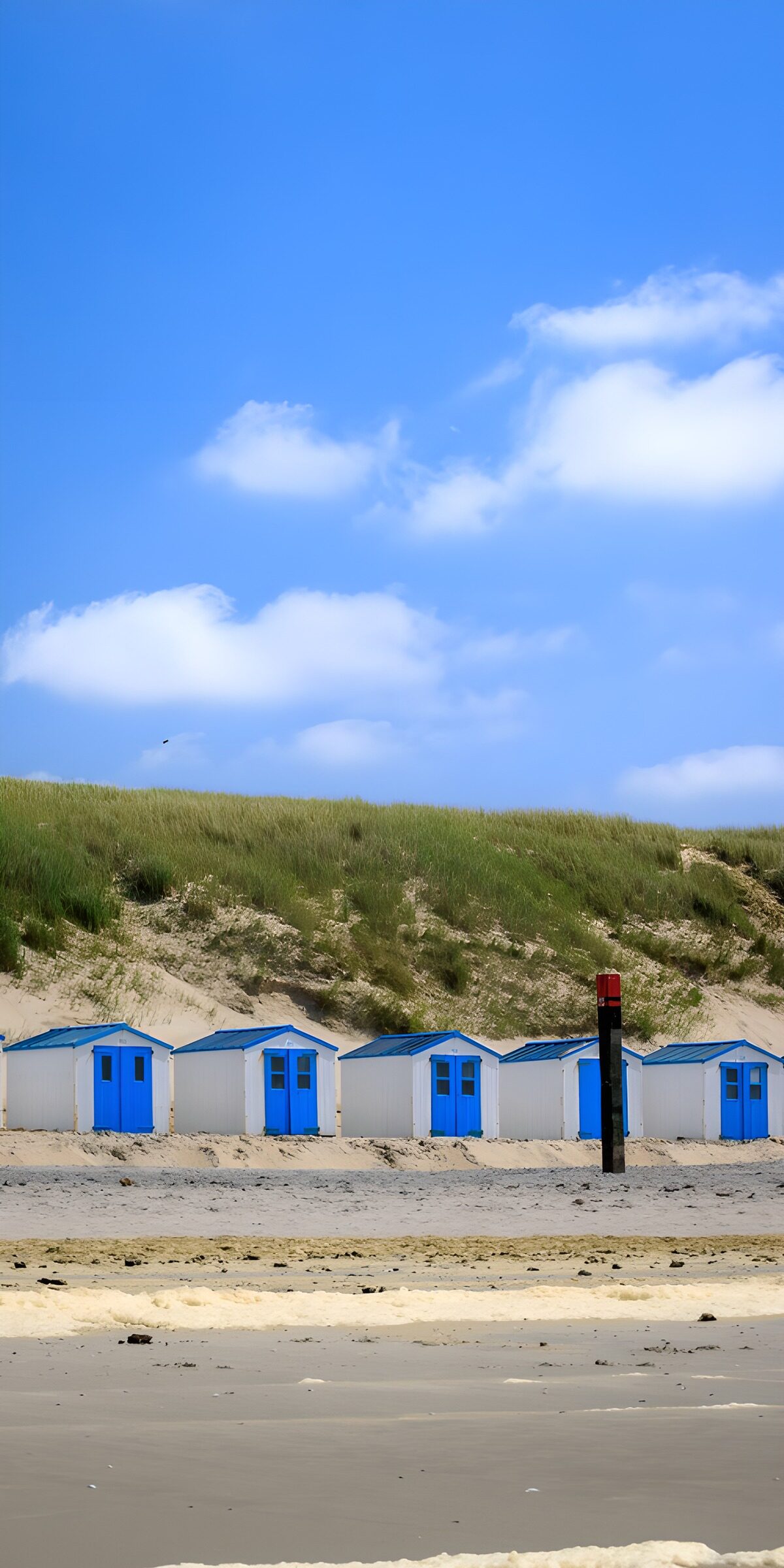 Blue and white beach huts by quiet dunes