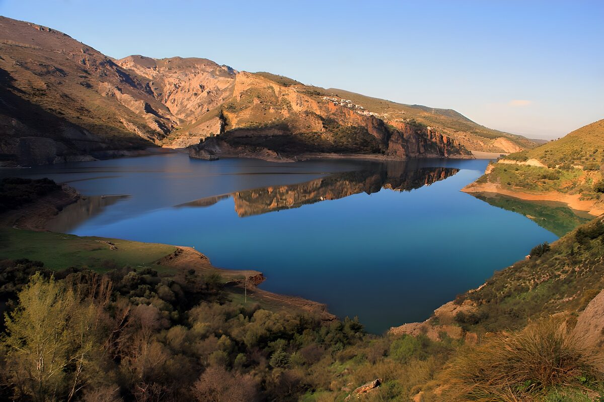 Blue lake beneath sunlit cliffs