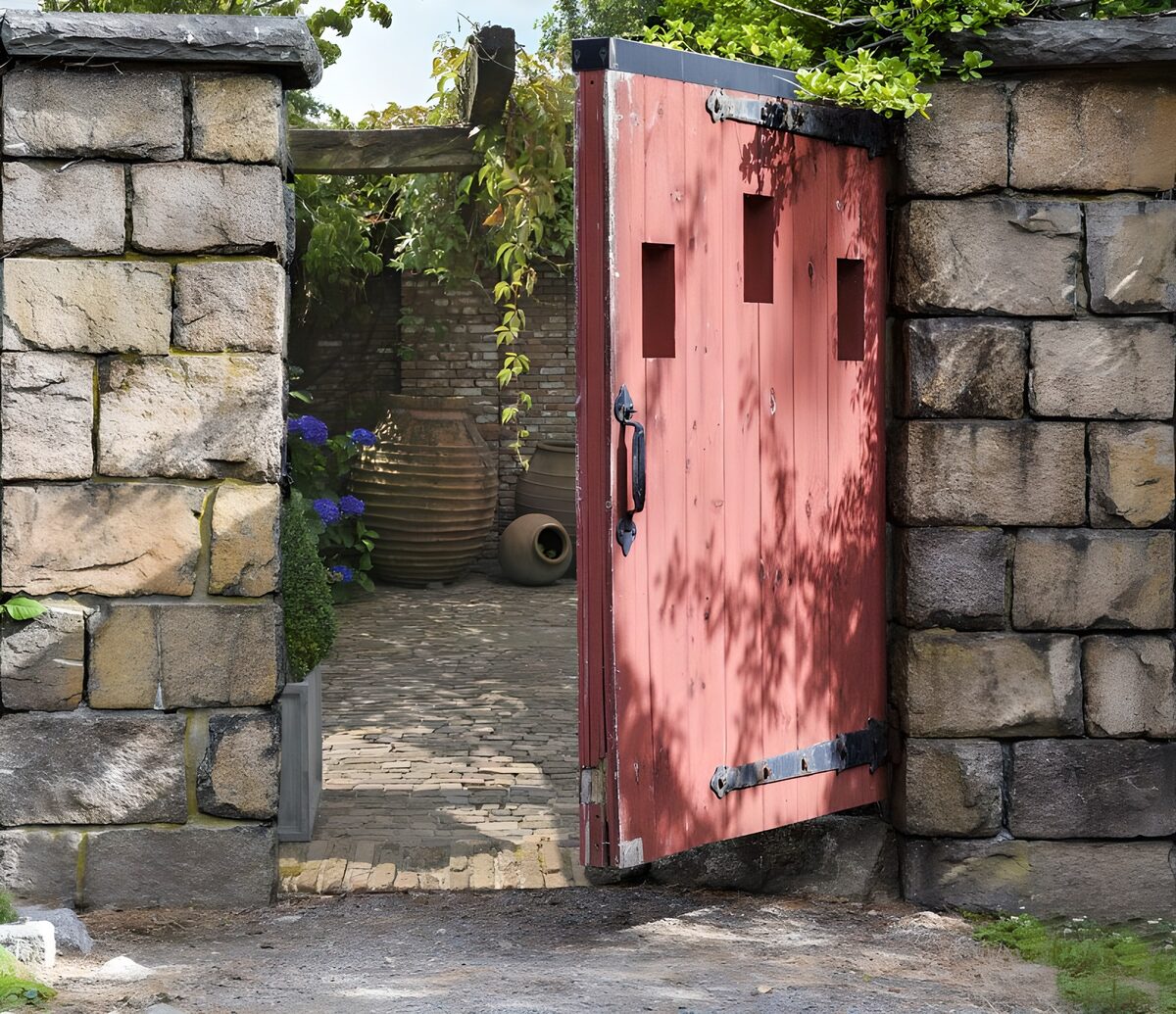 Open red gate to a sunlit courtyard
