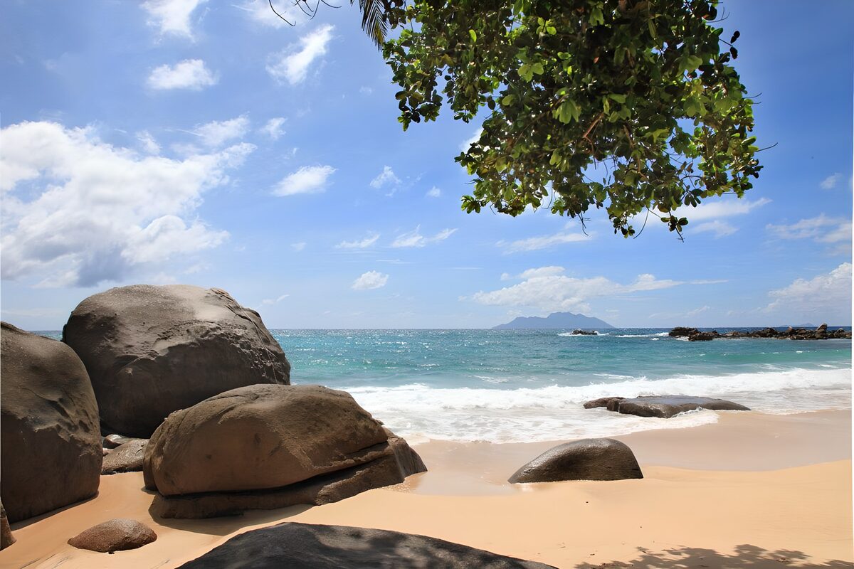 Sunlit beach with boulders and turquoise sea