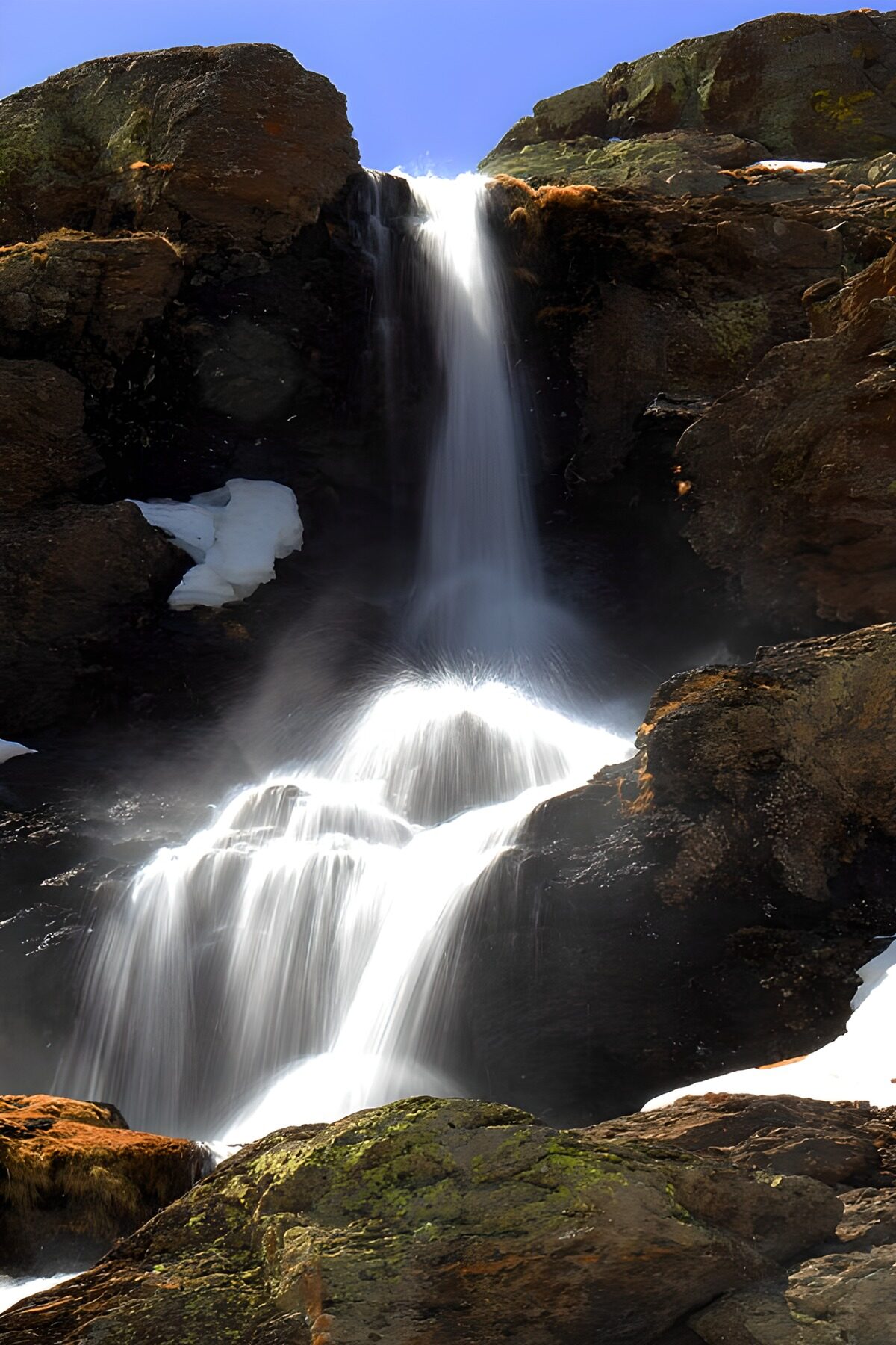 Sunlit waterfall over dark rock