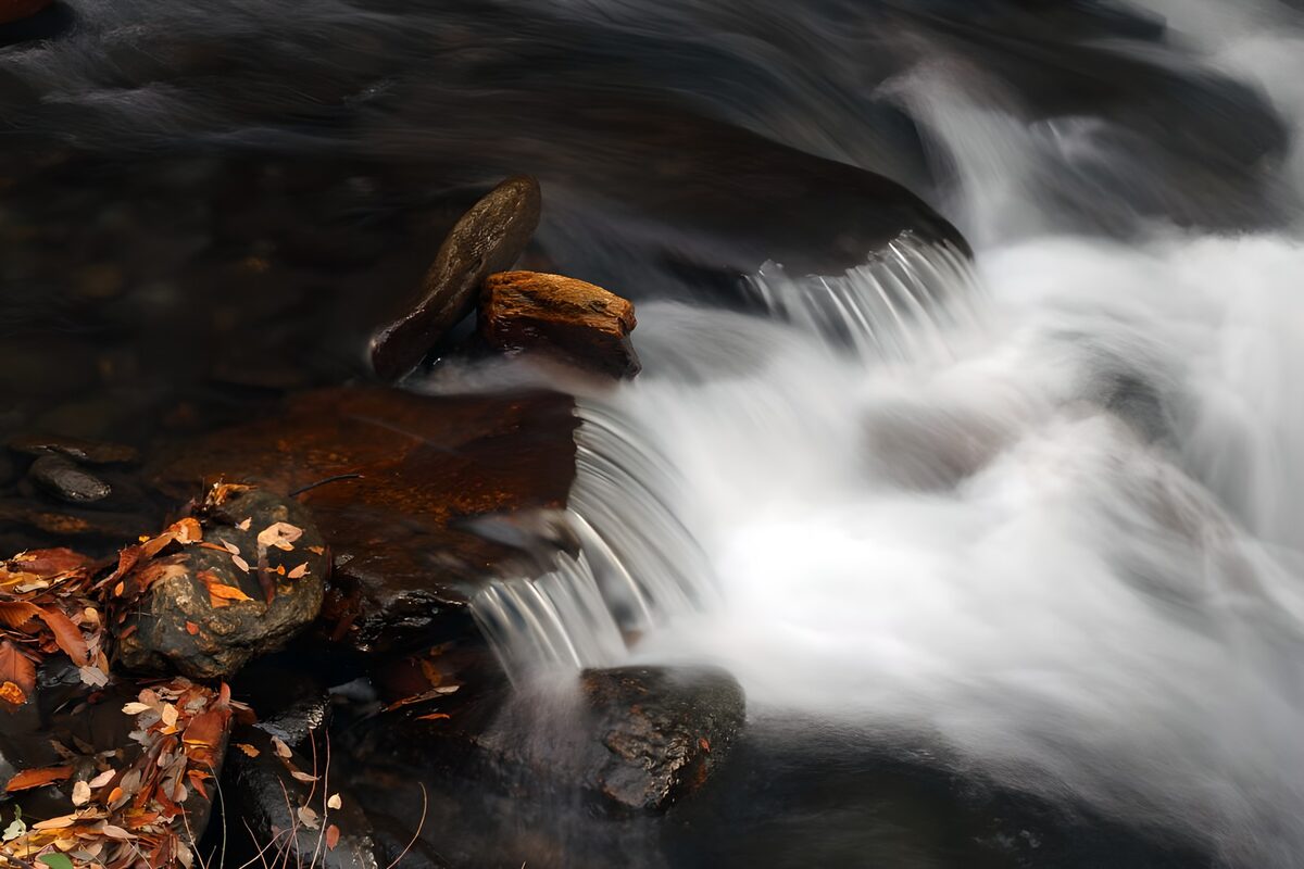 Autumn stream over dark rocks