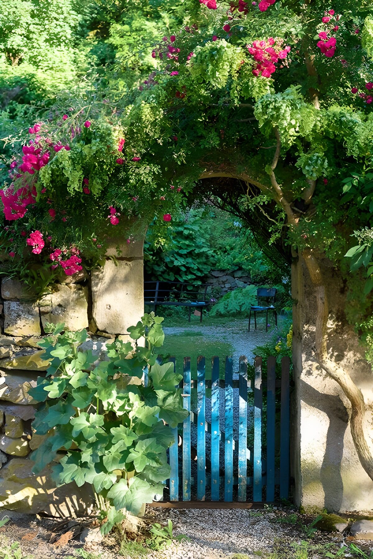 Blue garden gate beneath a leafy stone arch