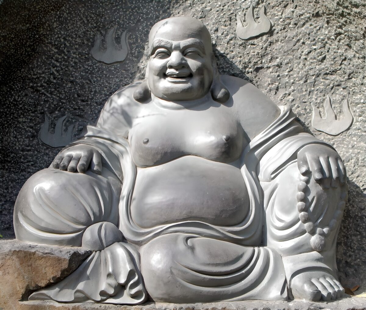 Smiling stone Buddha in sunlight