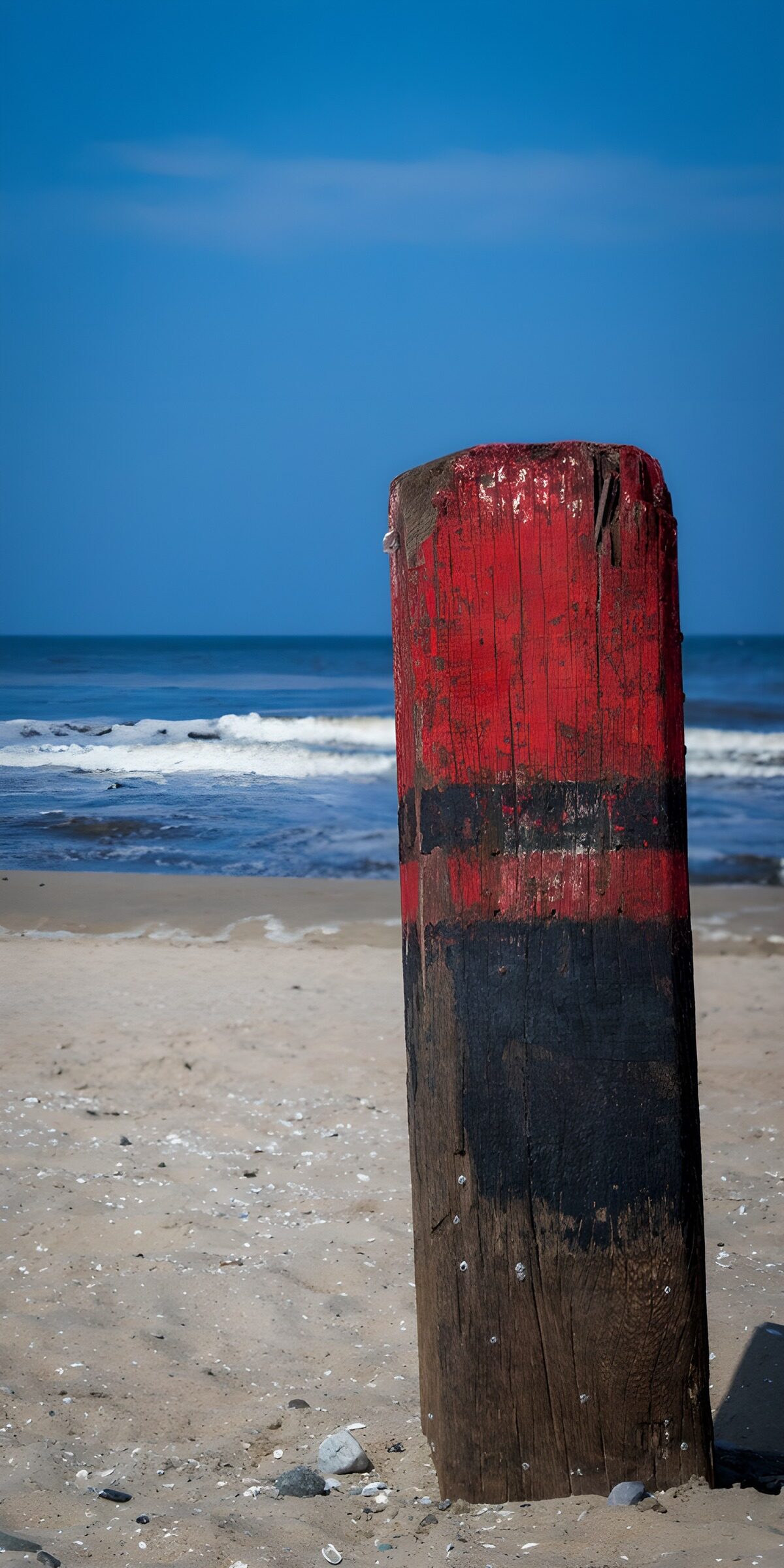 Weathered beach post beneath blue skies