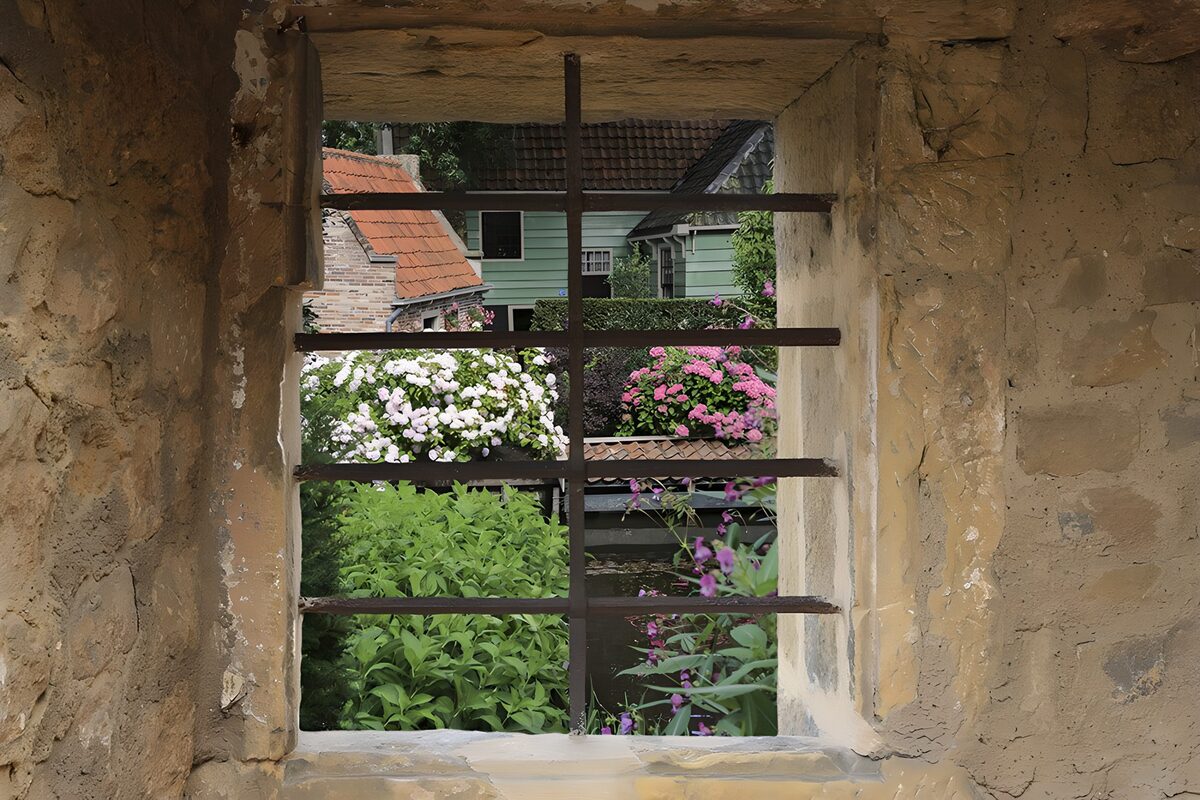 Quiet garden through a barred stone window