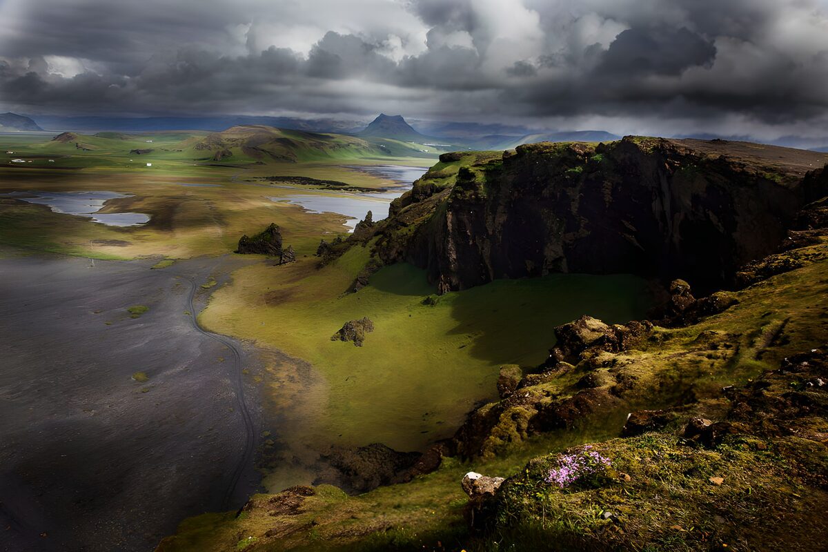 Dark cliff above a sunlit green plain