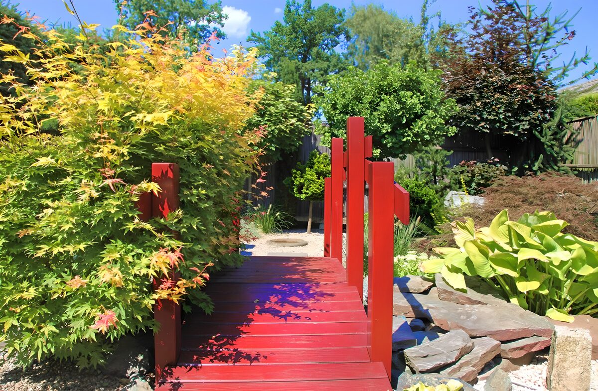 Red wooden bridge in a sunlit garden