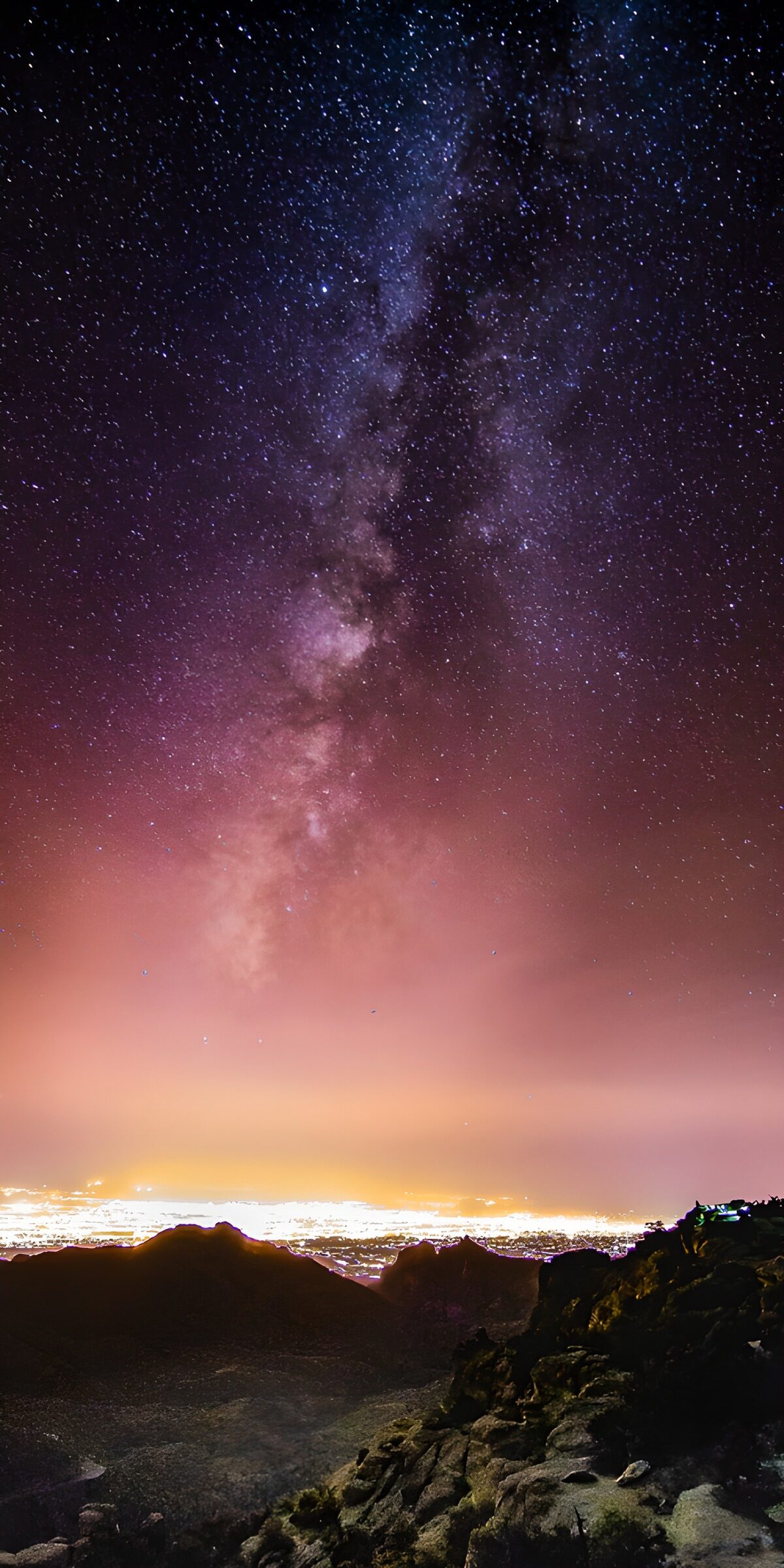 Milky Way above rocks and town lights