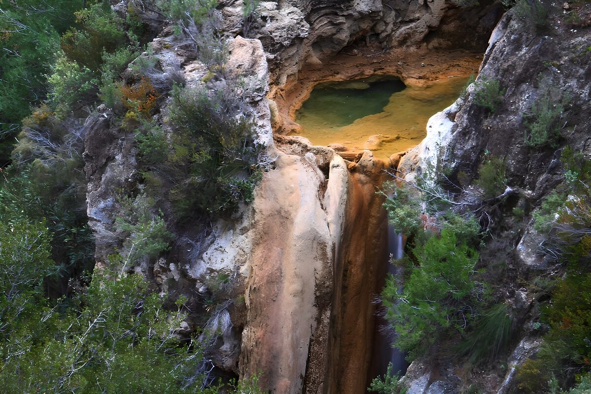 Green pool and waterfall in a rocky hollow