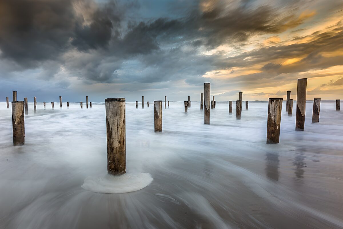 Weathered posts in the sunset surf