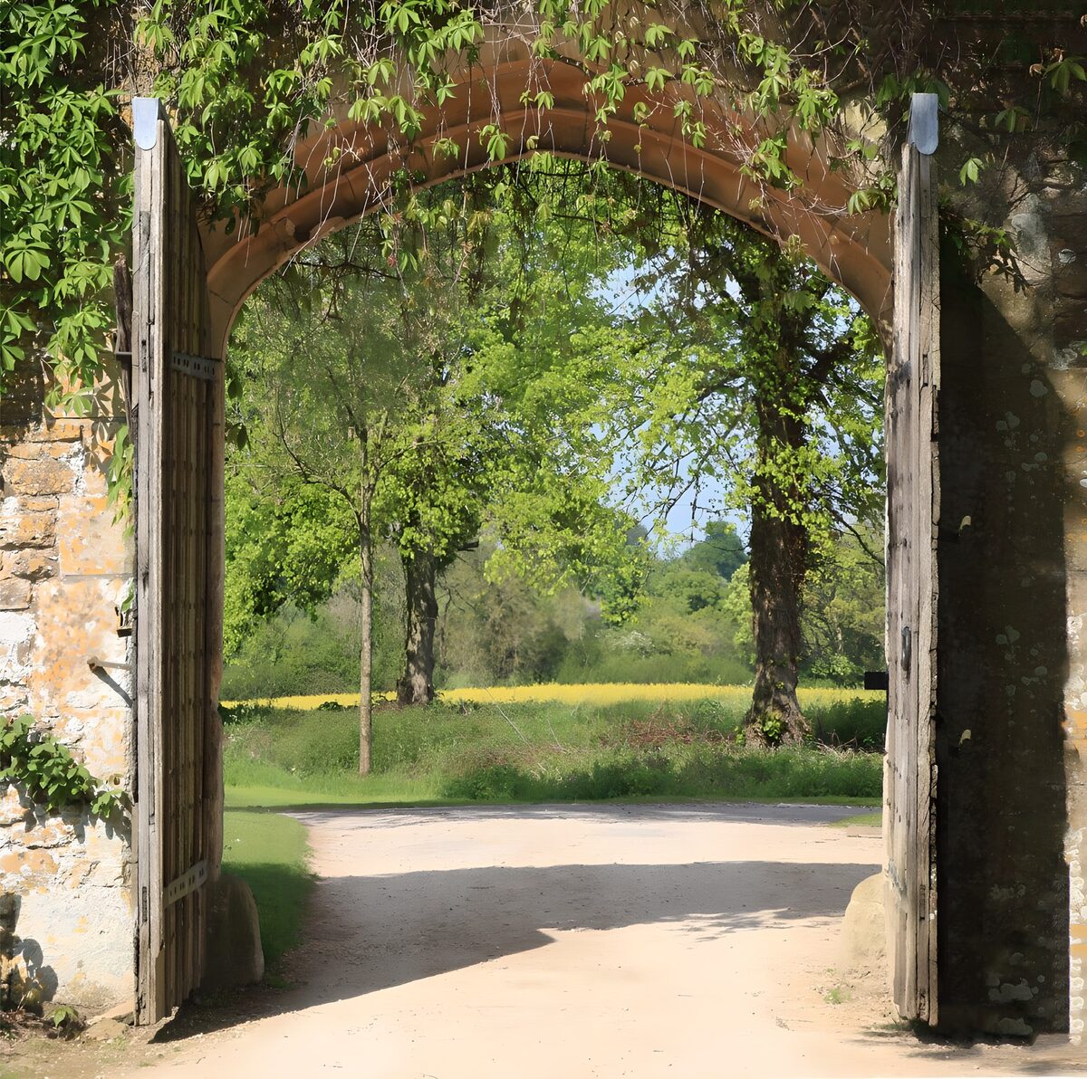 Sunlit wooden gates beneath a stone arch