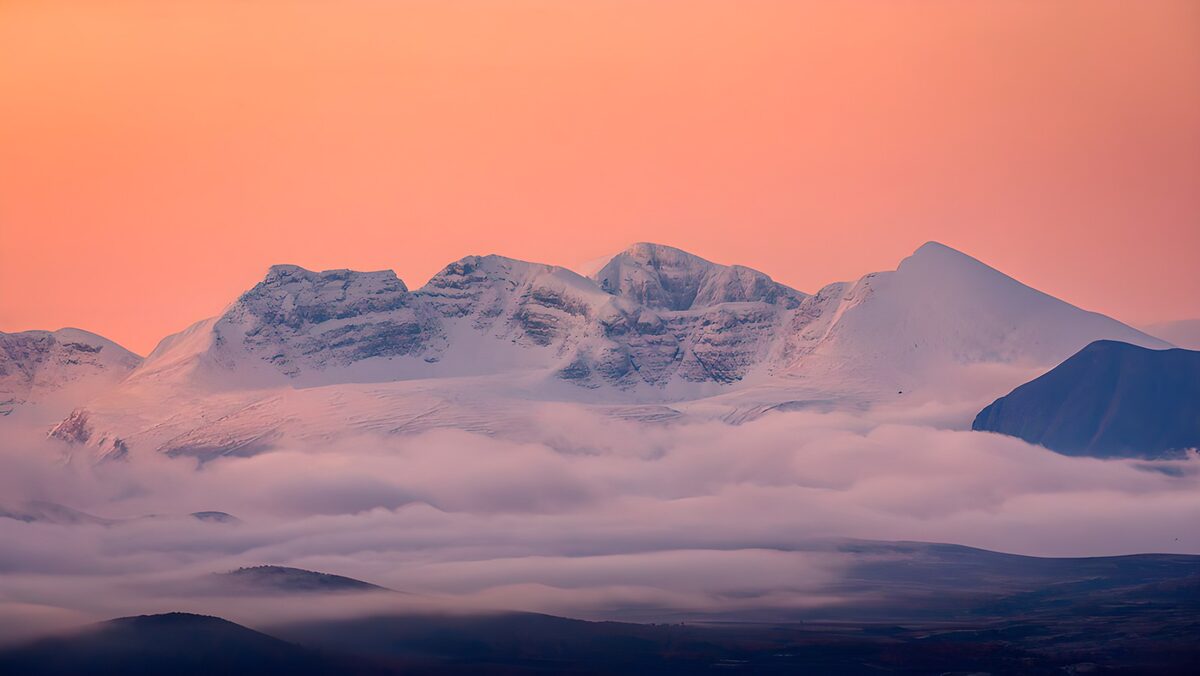 Snowy peaks beneath a coral-pink sky