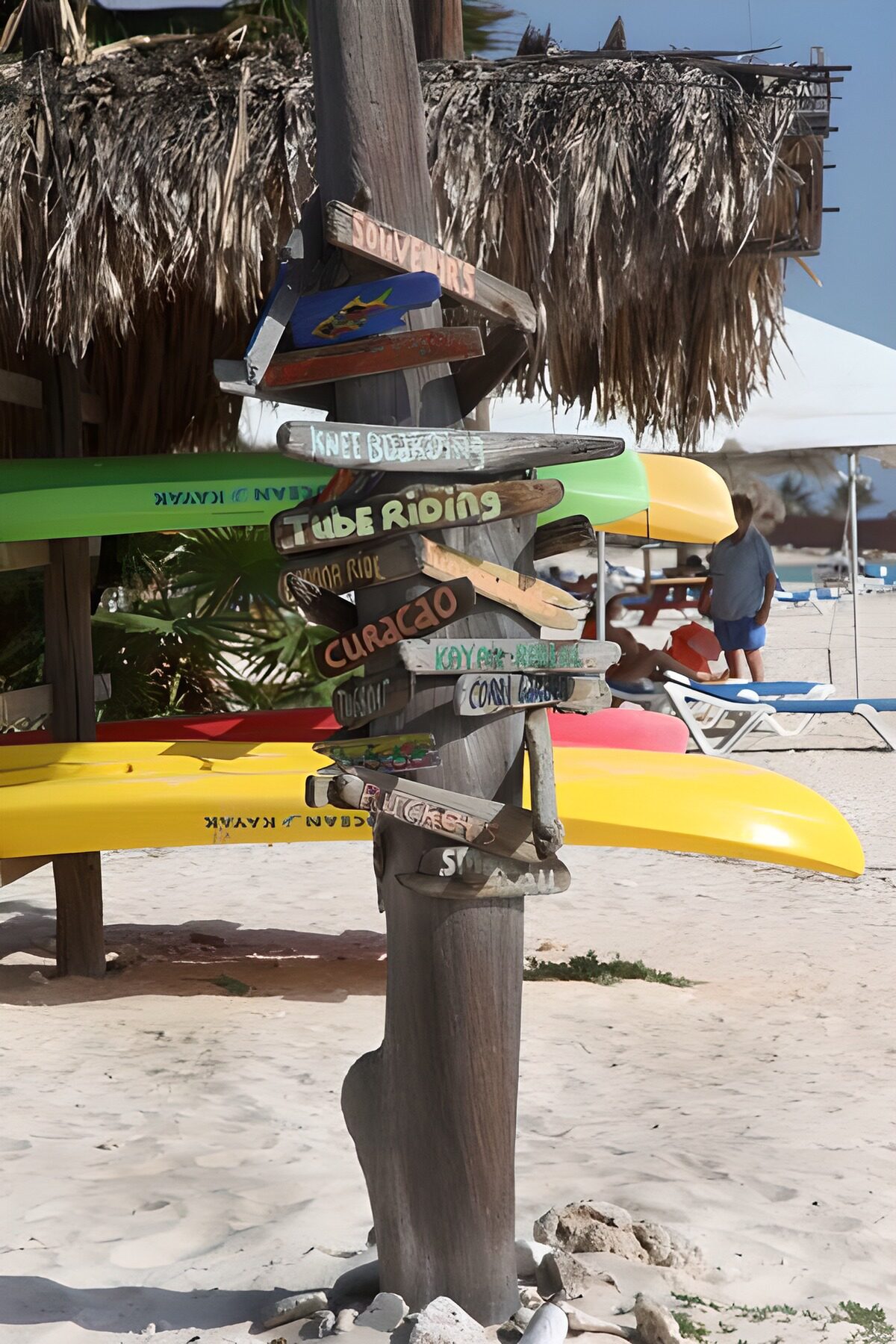Beach signpost and sunlit kayaks