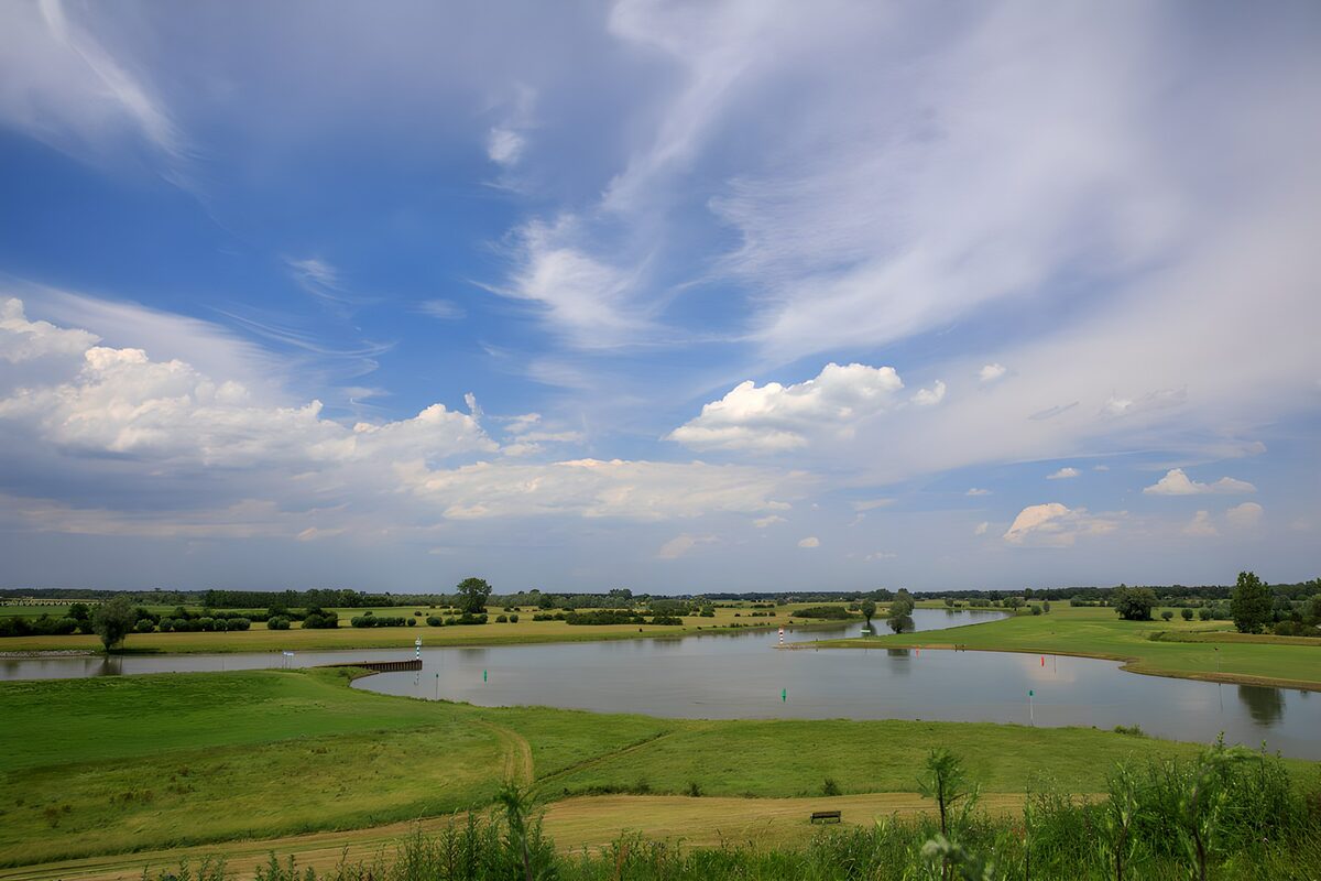 Pond and green banks beneath a wide sky