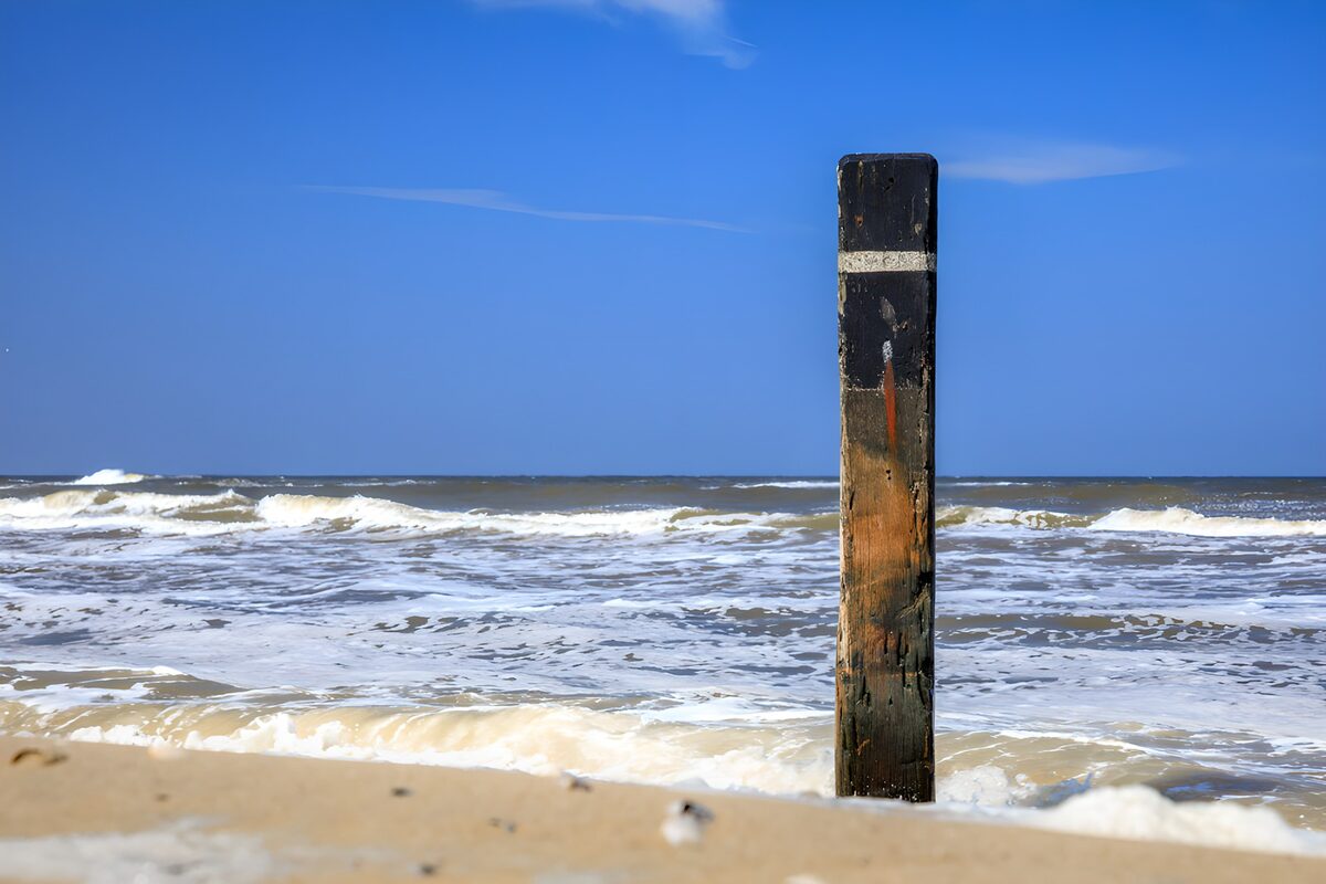 Weathered wooden post in sunlit surf
