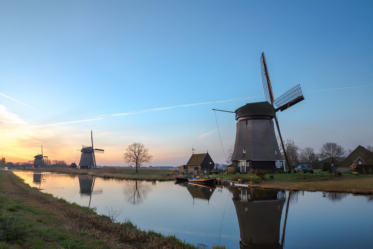 Three windmills beside a canal in warm light