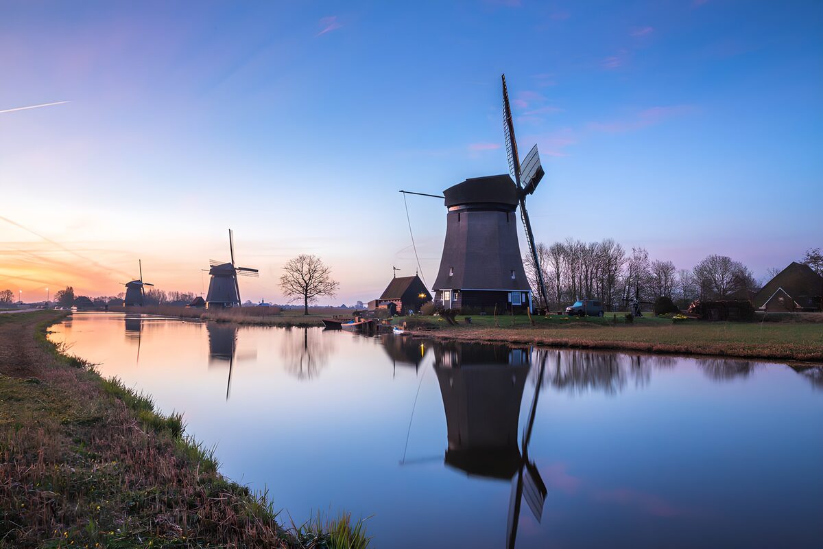 Three windmills beside a quiet canal