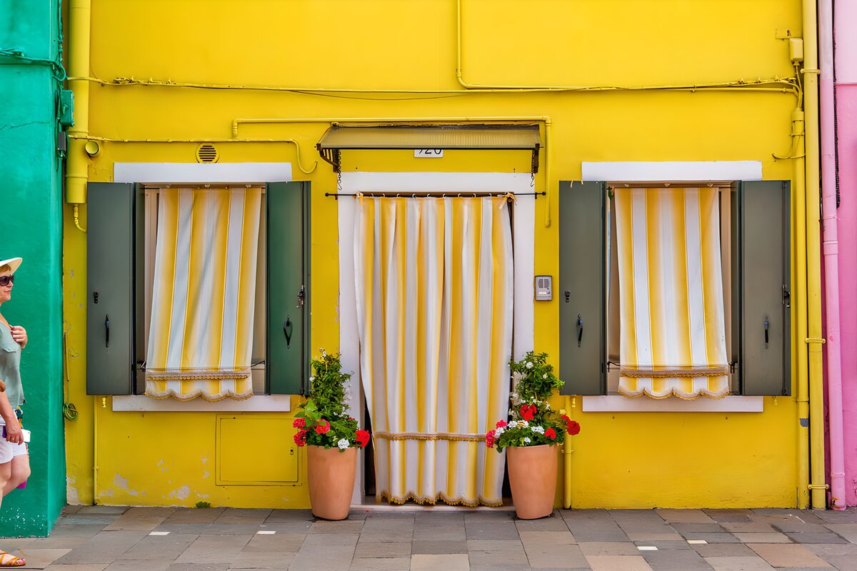 Sunlit yellow house with green shutters