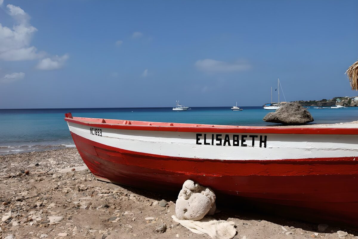 Red boat on a sunlit pebble beach