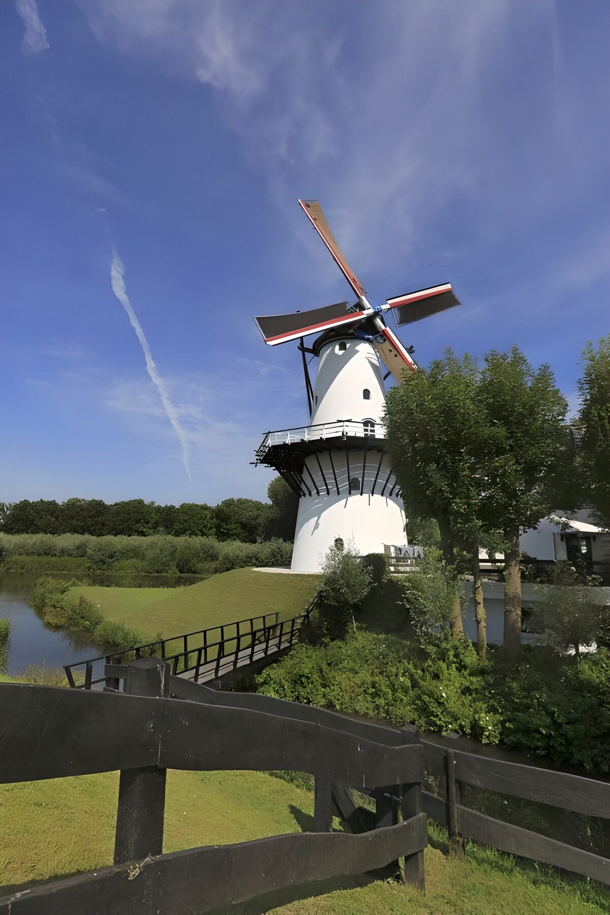White windmill beside a quiet waterway