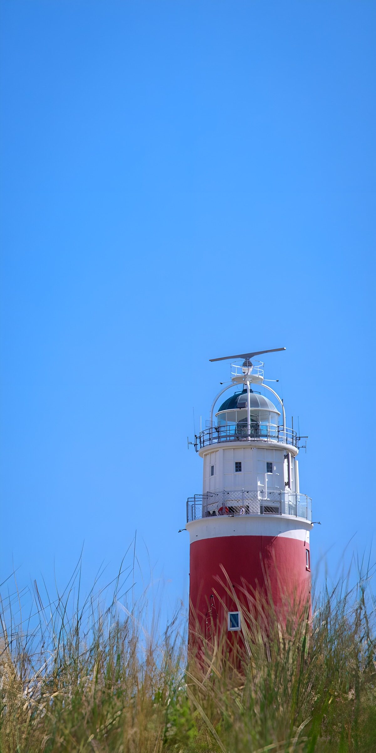 Red-and-white lighthouse under blue skies