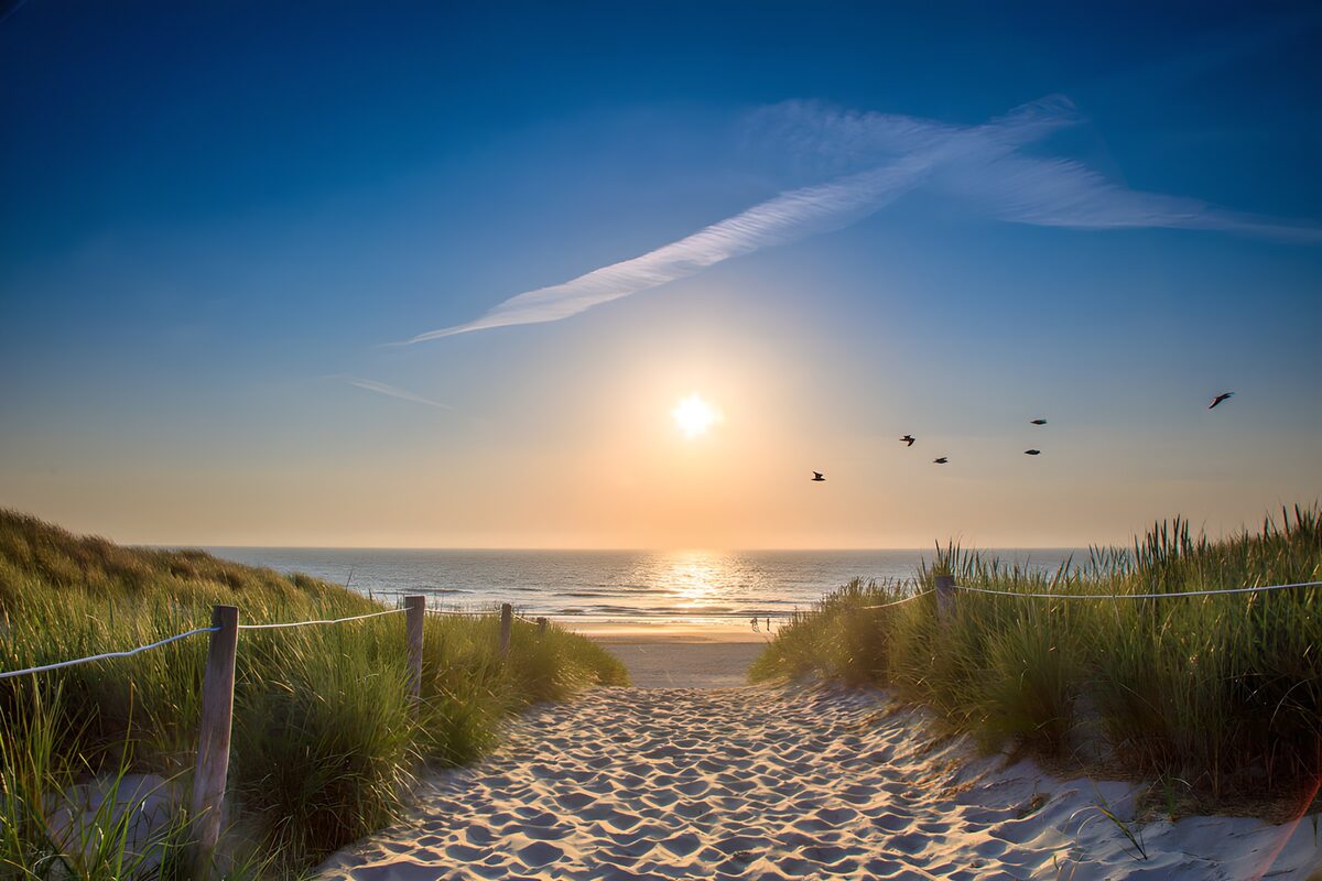 Sandy path through dunes at sunset
